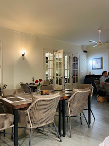 The image depicts an interior space of a venue in Thao Dien, Saigon. It features a dining area with several wooden tables and woven chairs. There are 