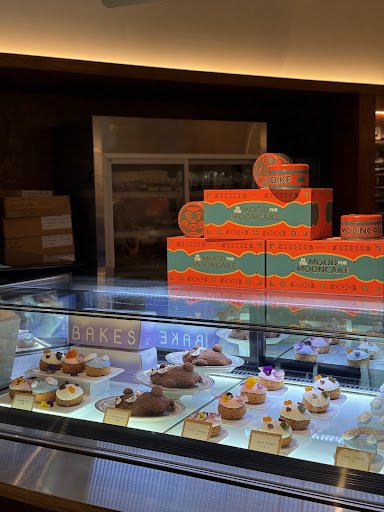 The image shows a display case in an interior setting of Thao Dien, Saigon with various pastries and desserts neatly arranged on plates for sale.