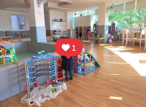 The image shows a spacious indoor play area designed for children's activities and learning. The room is well-lit with natural light streaming in thro