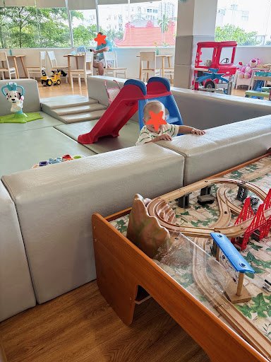 The image shows an indoor play area for children featuring a slide and various toys on the floor.