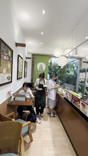 The image shows an interior view of a cafe or restaurant in Thao Dien, Saigon. There are three individuals visible: one staff member wearing black att