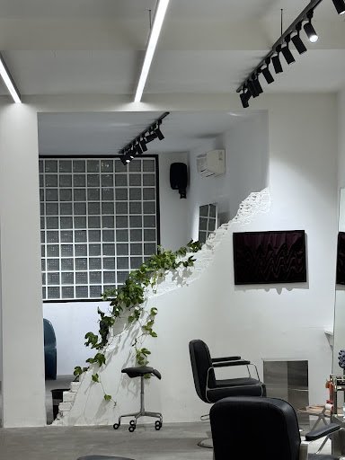 The image depicts an interior space that appears modern and stylish, likely a salon or beauty studio given the presence of chairs typically used for h