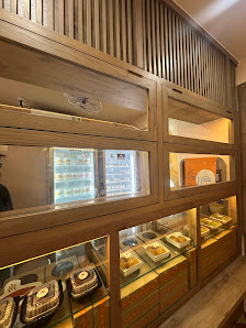 The image shows a well-lit interior of what appears to be a bakery or dessert shop with wooden shelving and display cases showcasing various packaged