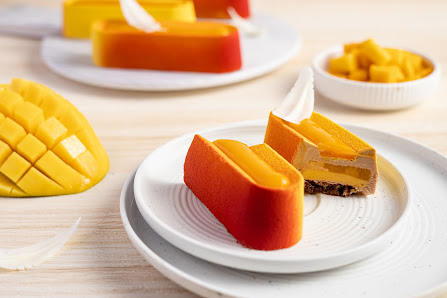 The image shows a plated dessert consisting of orange-colored fruit slices and what appears to be mango mousse or pudding in between the fruit, served