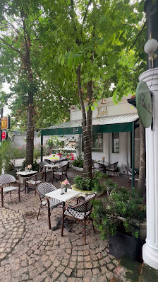 The image shows an outdoor seating area of a restaurant or café located in Thao Dien, Saigon. The setting includes several tables with chairs and pott
