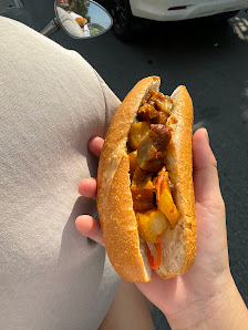 A hand is holding a hot dog filled with what appears to be chili and diced vegetables such as carrots or bell peppers.