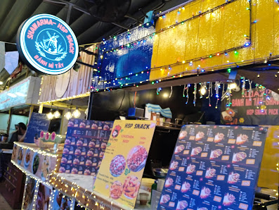 The image shows a food stall at an outdoor market or festival in Thao Dien, Saigon. The stall is named 'Sunflower Top Snack' and offers various snacks