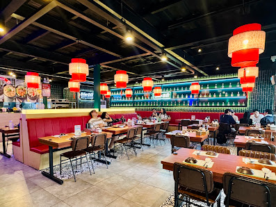 The image depicts the interior of a restaurant in Thao Dien, Saigon. It features red booth seating along the left side, wooden tables with black chair