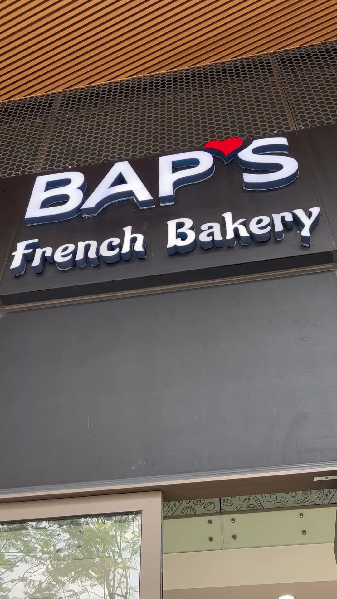 The image shows a storefront sign for 'BAP'S French Bakery'. The signage is in bold white and red letters on a dark background, with the word 'French'