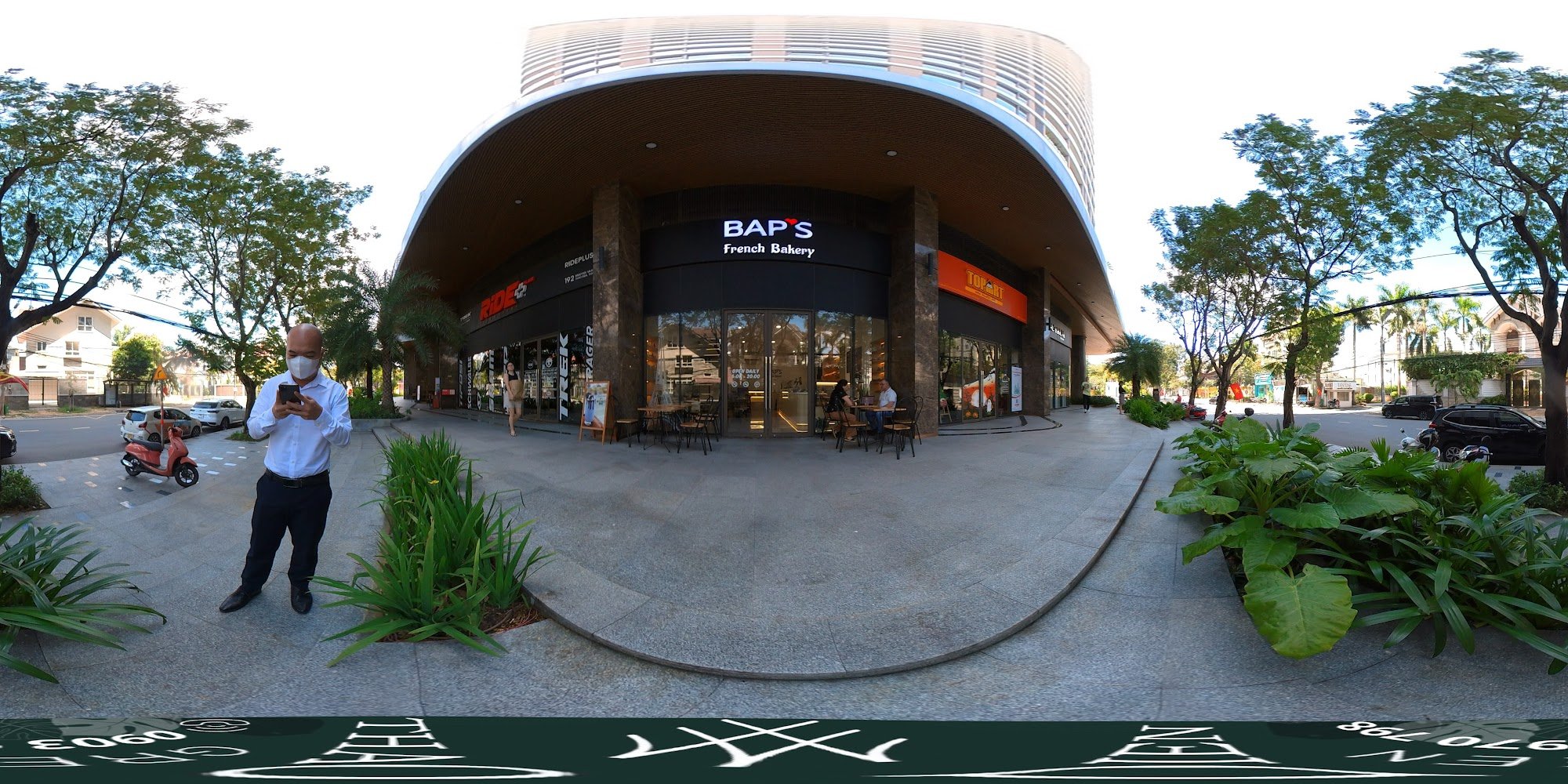 The image shows an exterior view of a French bakery named 'BAP'S' located in Thao Dien, Saigon. A man is standing on the sidewalk using his phone whil
