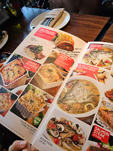 A close-up of an open menu from a restaurant in Thao Dien, Saigon, showcasing multiple food items with images and labels. The menu features dishes lik