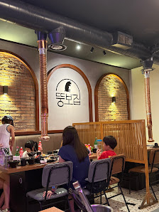 The image depicts the interior of a restaurant or café in Thao Dien, Saigon. It features wooden tables and chairs, a brick wall with arched openings, 
