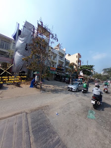 The image shows a street scene in Thao Dien, Saigon with various buildings and shops on the left side of the road. There are several people riding mot