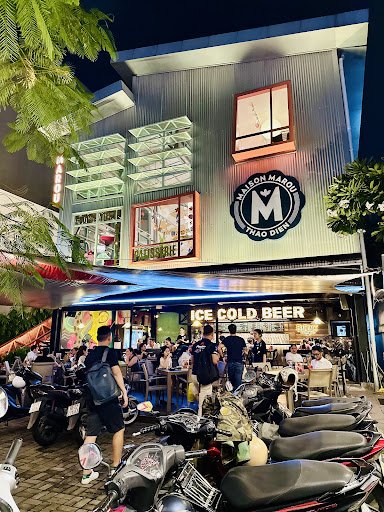 Nighttime exterior of a multi-story venue in Thao Dien, Saigon. The building features a modern facade with illuminated signage, including 'ICE COLD BE