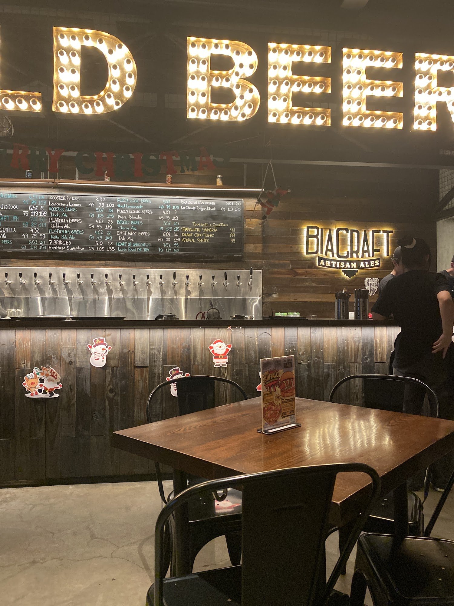 The image depicts the interior of a brewery or bar named 'OLD BEER' in Thao Dien, Saigon. Features include a large illuminated 'OLD BEER' sign with ma