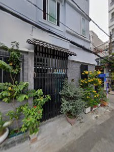 The image shows a residential building facade in Thao Dien, Saigon. The front of the house features an iron gate with plants and flowers on either sid