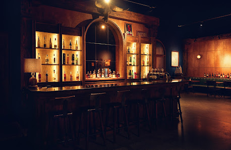 The image depicts a dimly lit bar area within an establishment named Thao Dien in Saigon. The interior features wooden paneling and shelves filled wit
