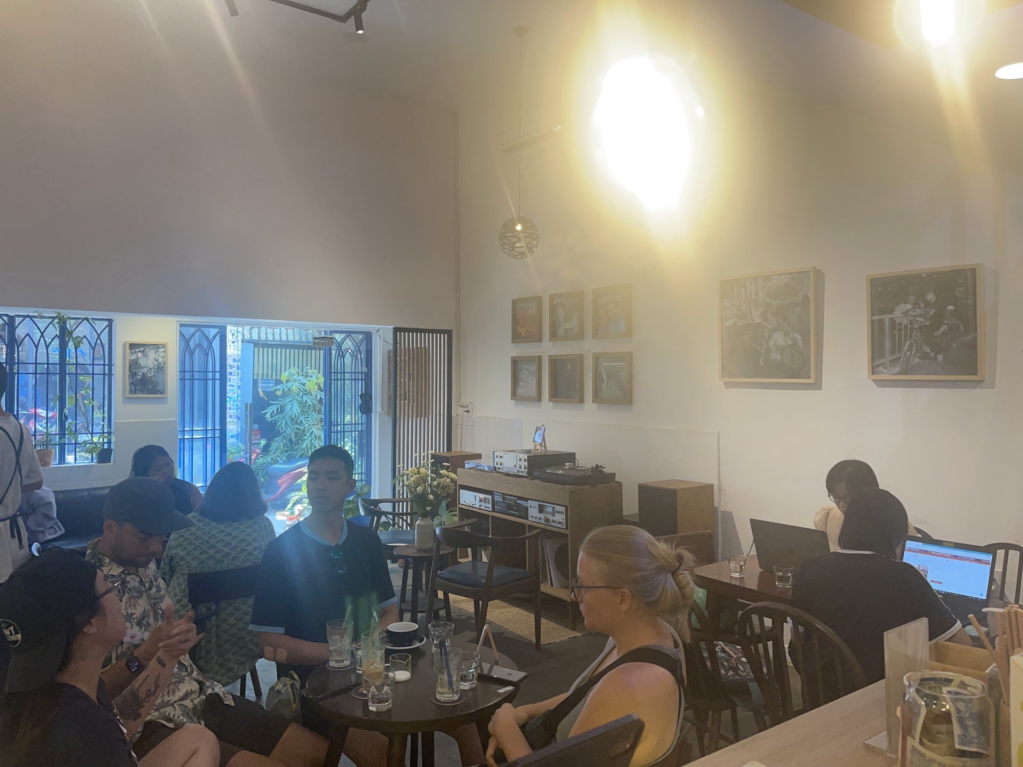 The image depicts an indoor setting of a cafe or restaurant in Thao Dien, Saigon. The space is well-lit with natural light coming through the large wi