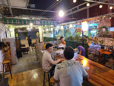 The image shows an interior view of a casual dining establishment in Thao Dien, Saigon. Patrons are seated at the bar and tables, engaged in conversat