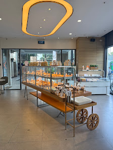 The image shows an interior view of a modern bakery or café in Thao Dien, Saigon. The space is well-lit with natural light coming through the large gl