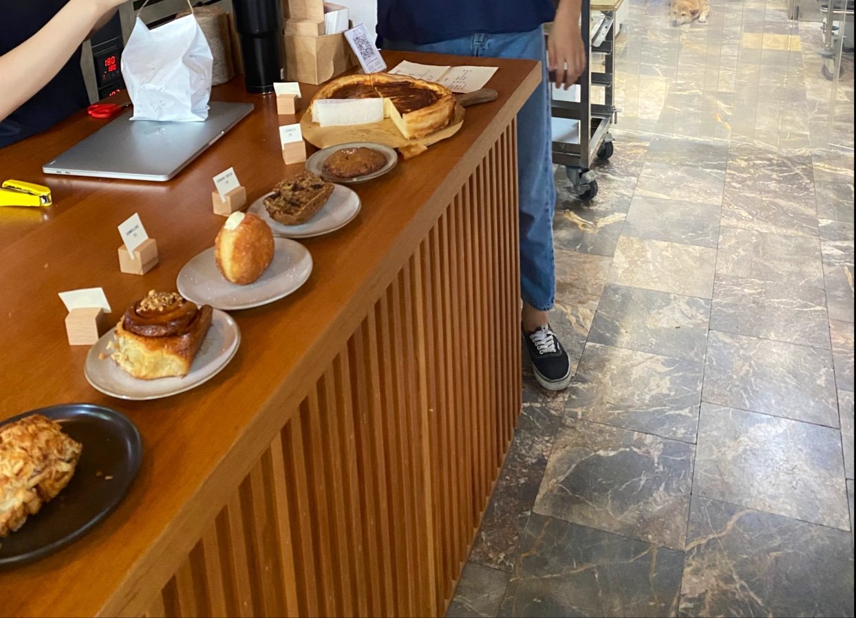 The image shows a counter in what appears to be a cafe or bakery setting within Thao Dien, Saigon. Various pastries and desserts are displayed on the 