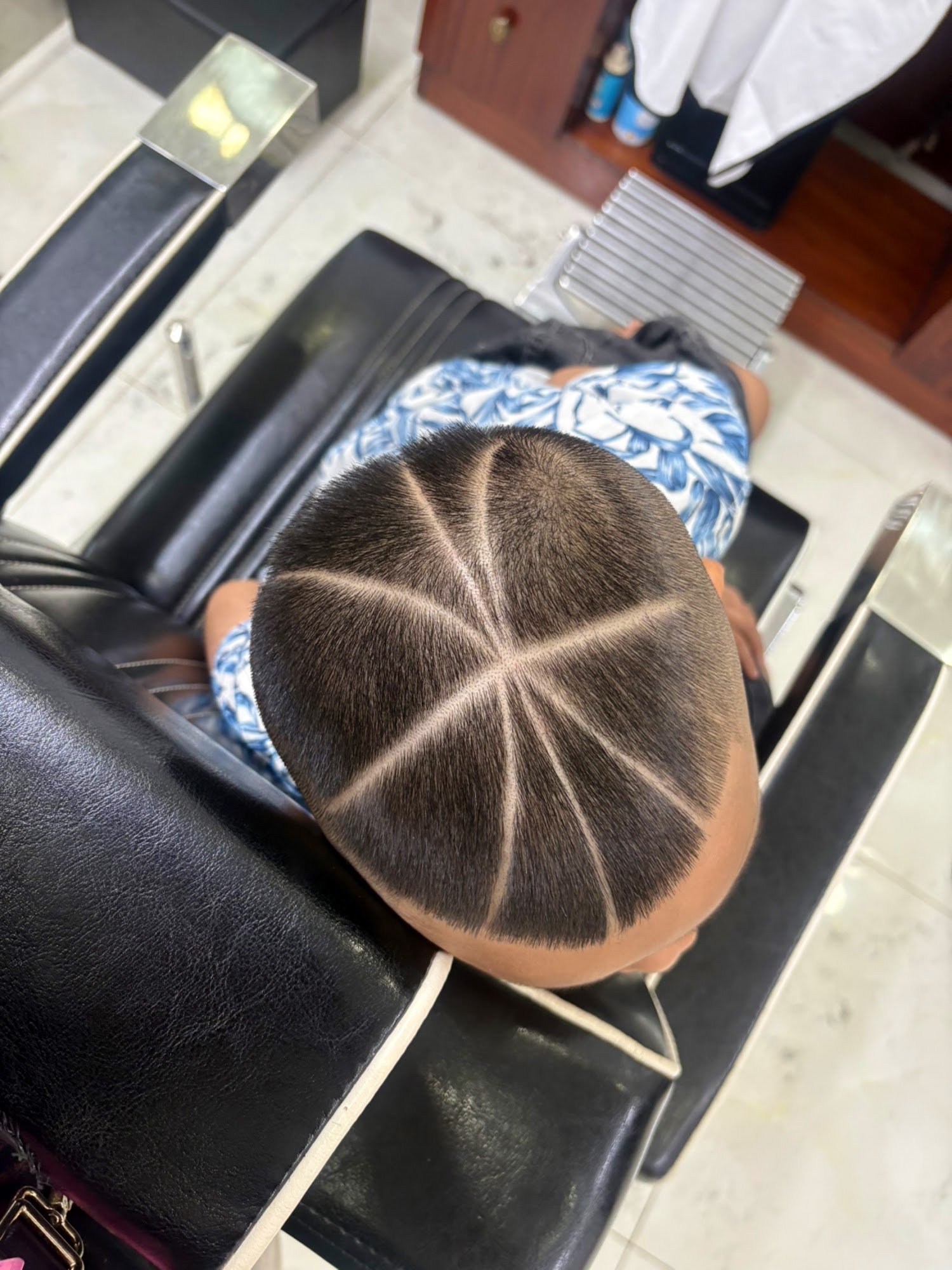 A person is seated in a barber's chair receiving a haircut at Thao Dien, Saigon.