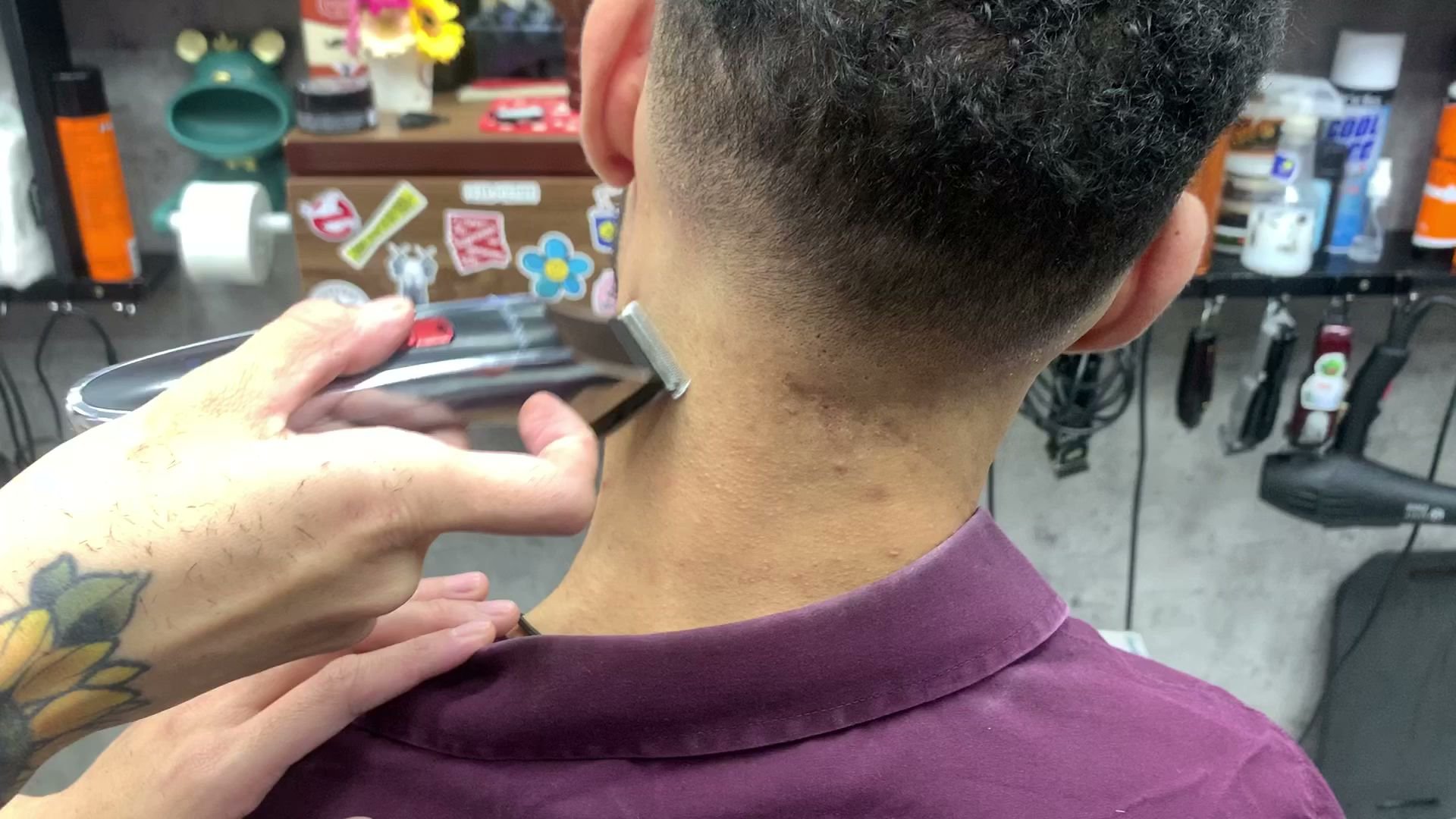 The image depicts a barber giving a haircut in what appears to be a barbershop or salon setting.