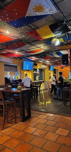 The image shows an interior view of a restaurant or bar in Thao Dien, Saigon. The ceiling is adorned with colorful flags and string lights, creating a