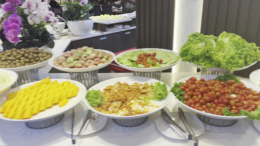 A buffet setup at a venue in Thao Dien, Saigon, featuring multiple dishes on a table. Visible items include yellow cheese cubes, cherry tomatoes, larg