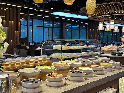 A well-lit interior of a restaurant or hotel dining area in Thao Dien, Saigon, featuring a buffet counter with various dishes including bowls of salad