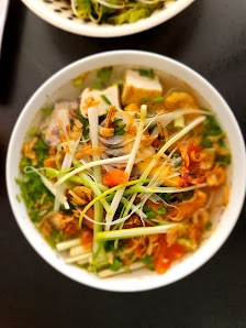 A bowl of noodle soup containing various vegetables and possibly tofu or meat slices.