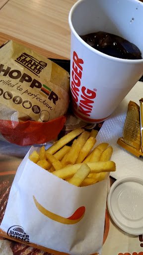 The image shows a meal from Burger King consisting of French fries in their branded paper container and a cup of soda with the brand name visible on i