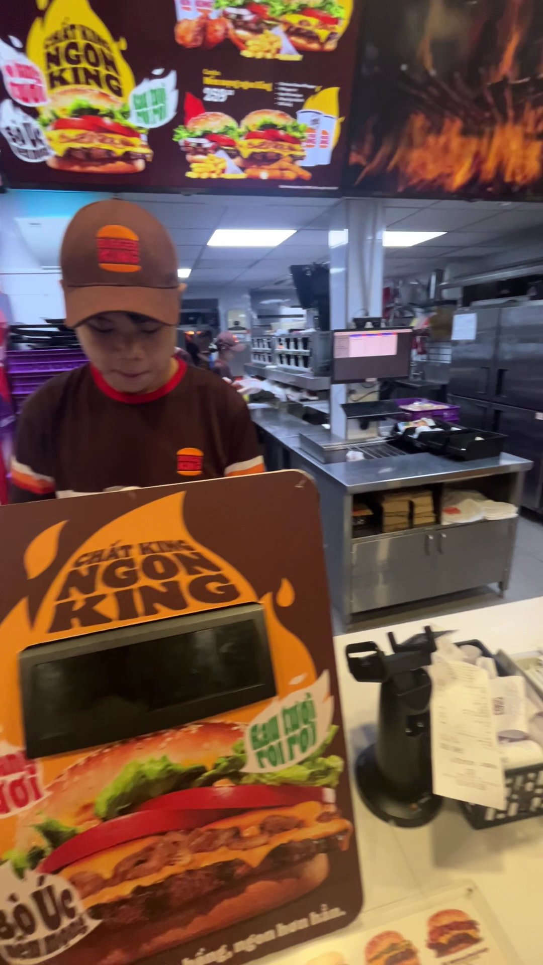 The image shows an interior view of a fast-food restaurant where employees are working behind the counter.