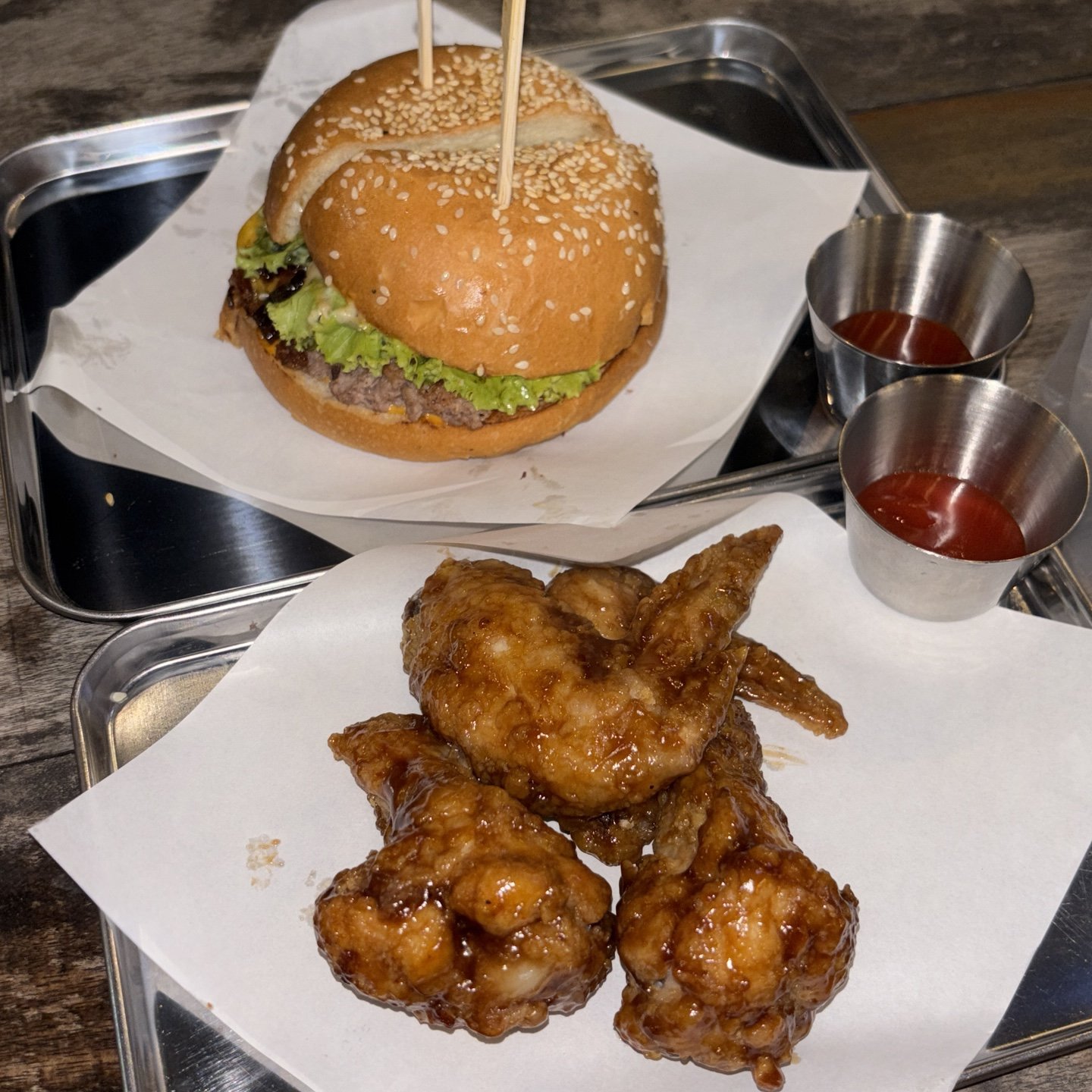The image shows a plated meal consisting of two sesame seed buns containing lettuce and what appears to be beef patties, skewered with wooden toothpic