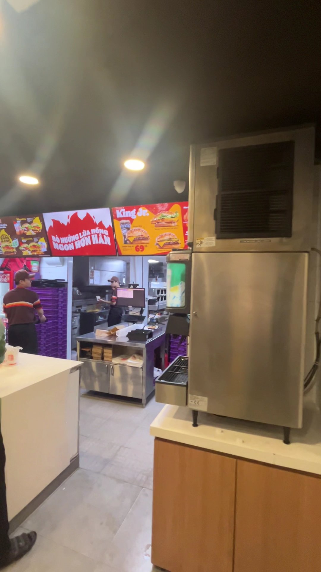 The image shows an interior view of a fast-food restaurant named 'King Jr.' with employees working behind the counter and various food items displayed