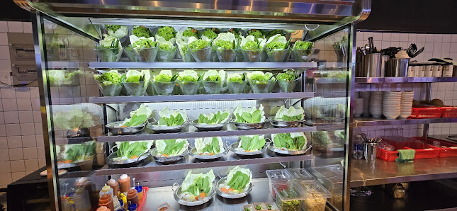 The image shows a well-lit interior of what appears to be a modern restaurant or food establishment with stainless steel shelving units displaying var