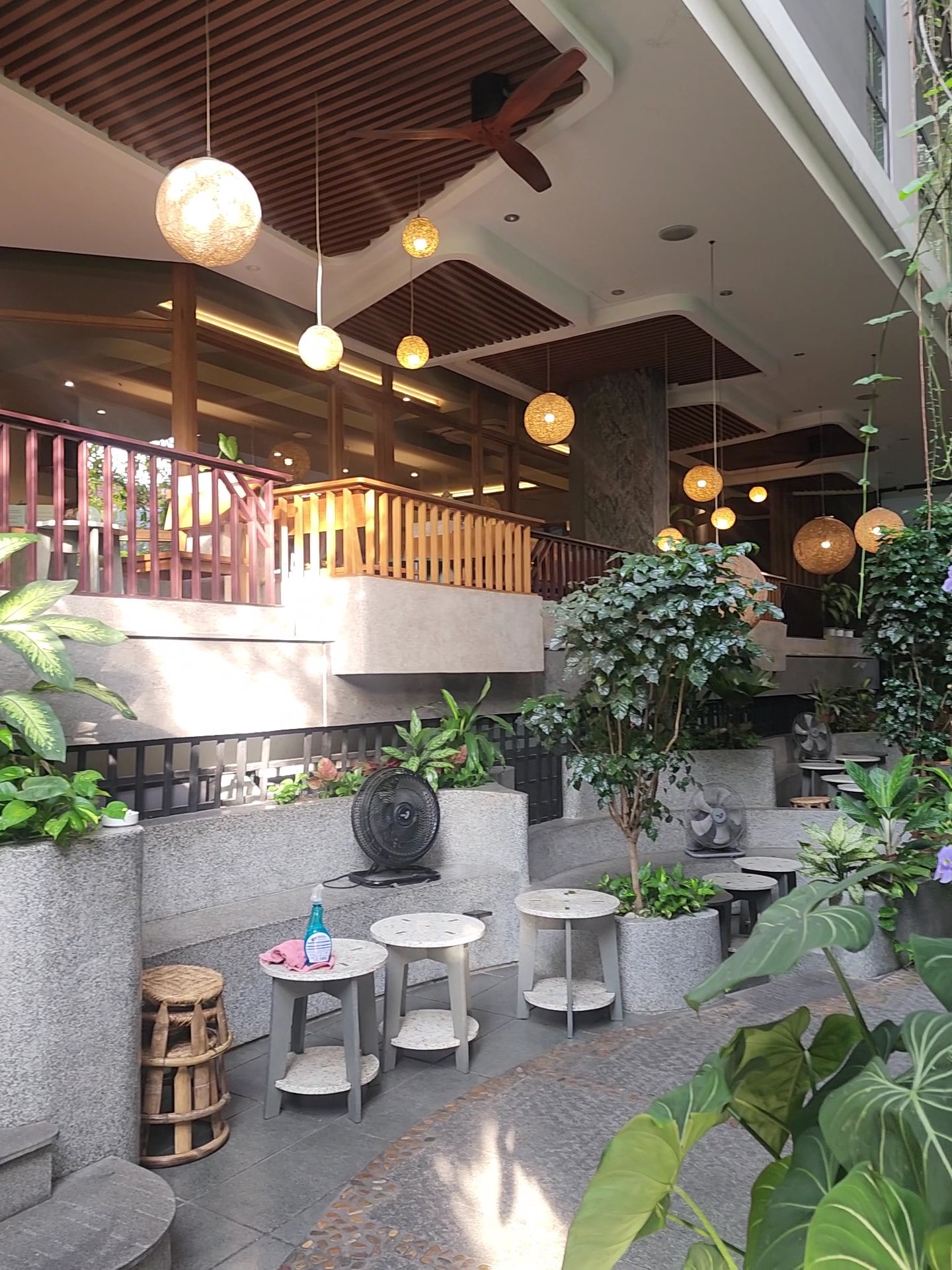 The image depicts an indoor seating area of a restaurant or cafe in Thao Dien, Saigon. The space is well-lit with hanging pendant lights and natural l