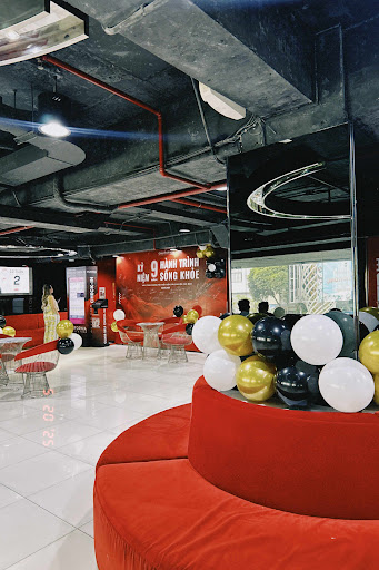 The image shows an interior space of a venue in Thao Dien, Saigon with modern decor and red seating arrangements around tables adorned with black, gol