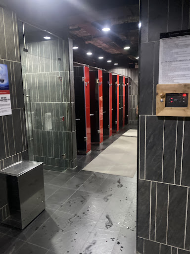 An interior view of a public restroom in Thao Dien, Saigon. The space features a row of red and black stalls, green-tiled walls on the left, dark gray