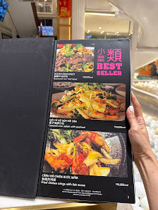 A person is holding a menu showcasing various dishes and their prices in what appears to be an indoor setting with bright lighting.