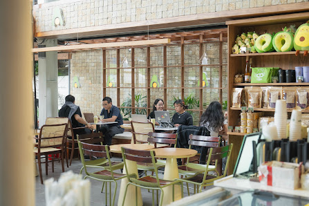 The image depicts the interior of a café or coffee shop in Thao Dien, Saigon. It features several patrons seated at round tables with green and brown 