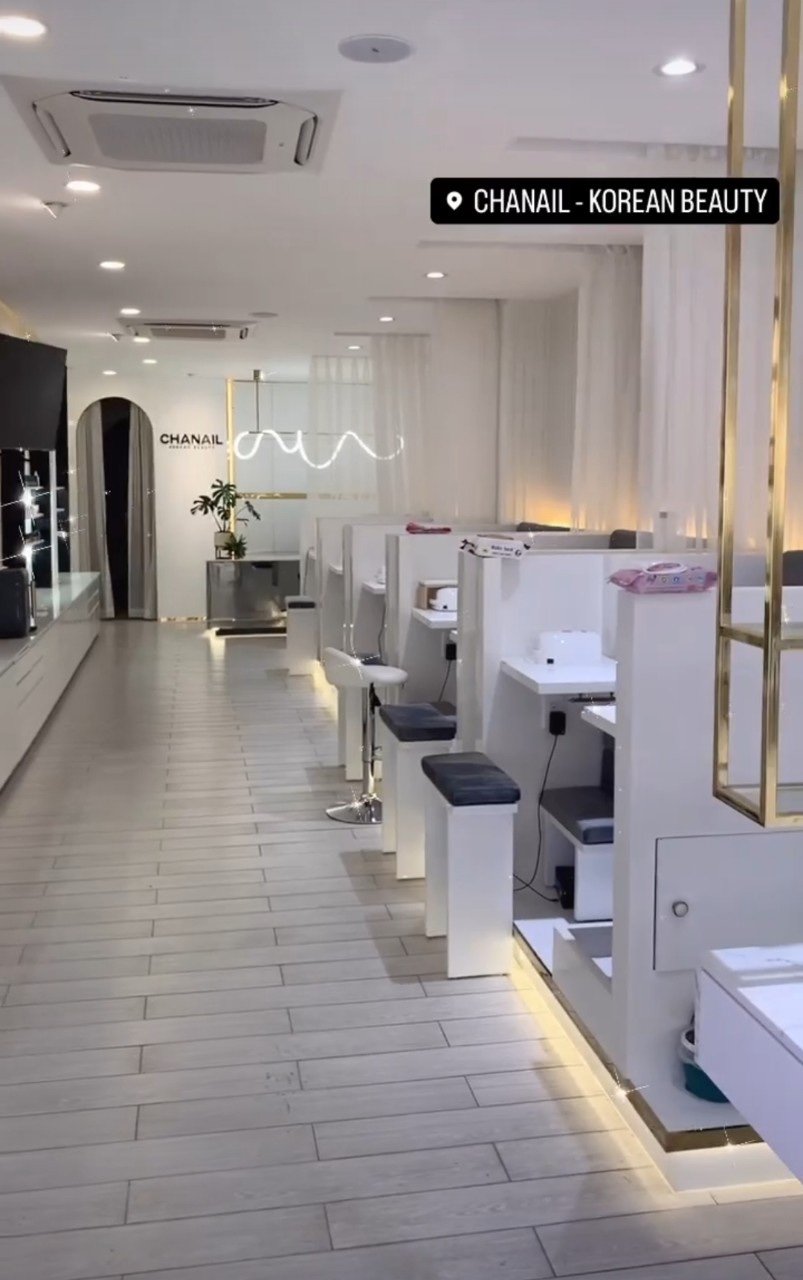 The image shows a modern and clean interior of what appears to be a beauty salon or spa with white decor, illuminated by soft lighting. The flooring i