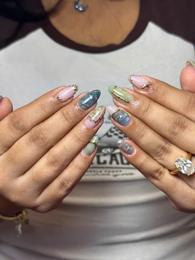 A close-up of a person's hands displaying intricately designed nail art featuring various colors and glittery accents.