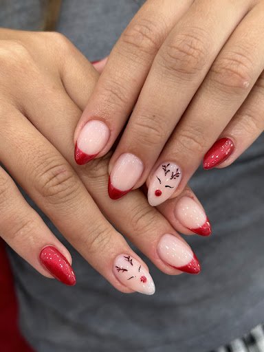 A close-up of a person's hands displaying elaborately decorated fingernails painted in red and white with festive designs resembling reindeer.