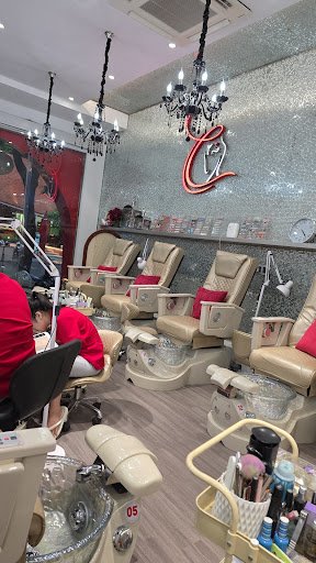 The image shows an interior view of a nail salon or beauty parlor. The space is well-lit with multiple chandeliers hanging from the ceiling, and featu