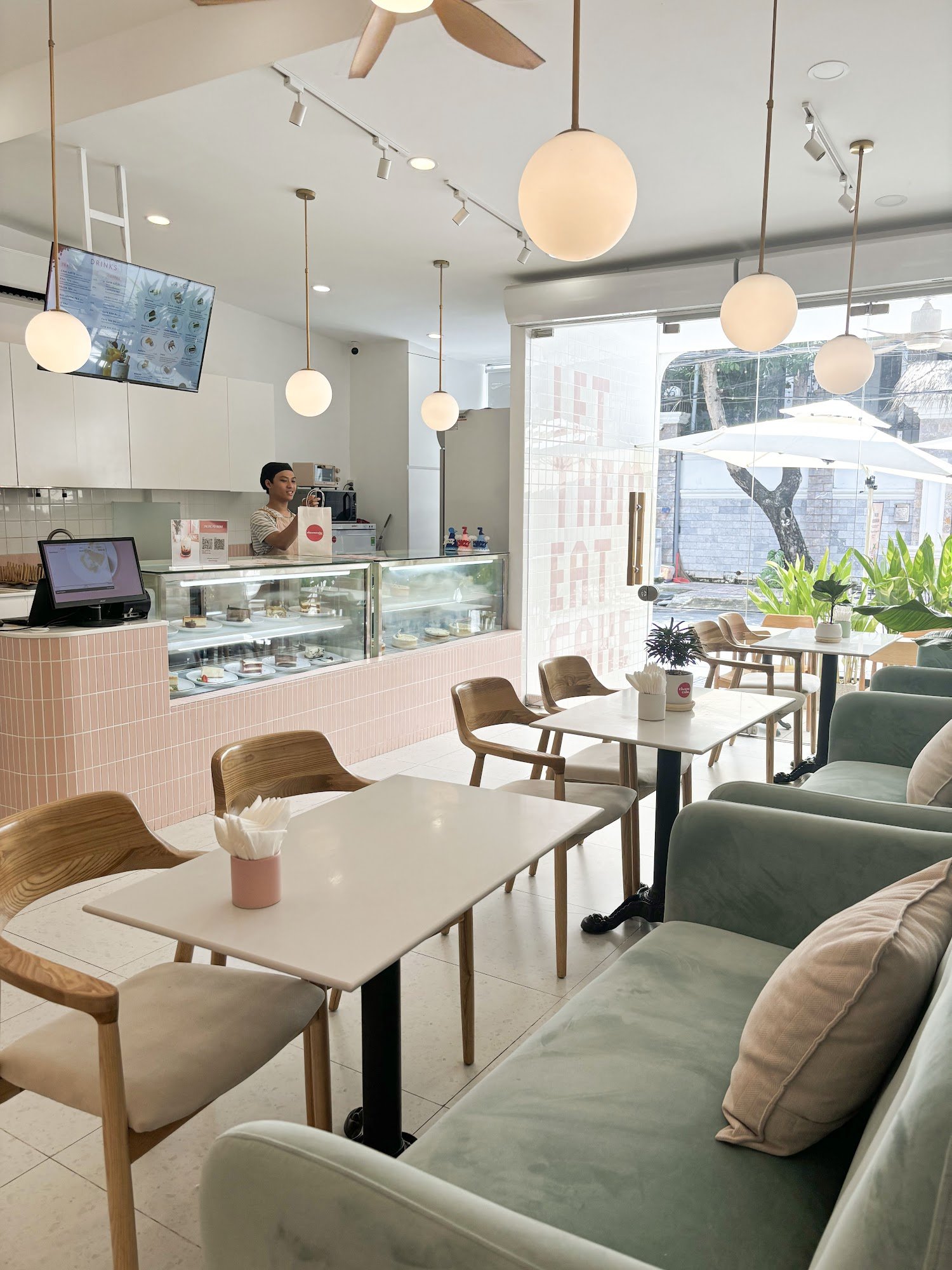 The image depicts an interior view of a modern cafe or restaurant in Thao Dien, Saigon. The space is well-lit with natural light coming through the la