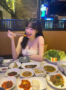 A woman is dining at a restaurant in Thao Dien, Saigon, with multiple Vietnamese dishes on the table. The table features various dishes including spri