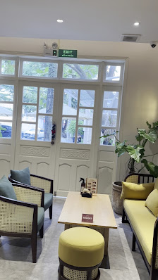 The image shows a well-lit waiting area inside a venue in Thao Dien, Saigon with large windows allowing natural light to enter. There are two sofas an