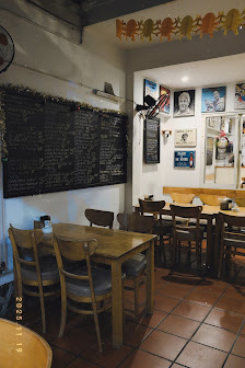 The image shows an interior view of a restaurant or cafe in Thao Dien, Saigon. The space features wooden tables and chairs arranged around the room, w