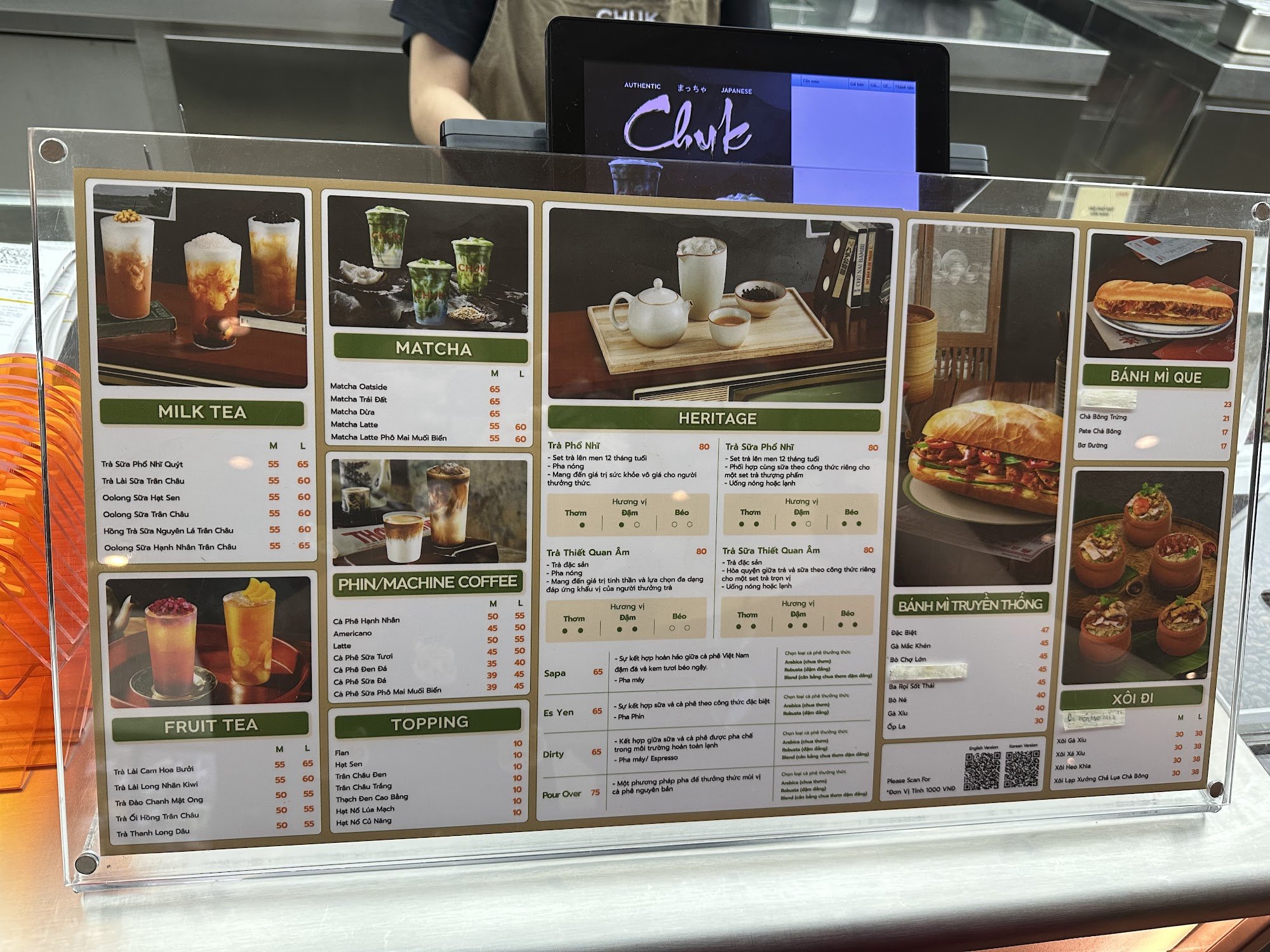 A menu board at a beverage and food stall displaying various drink options such as milk tea, matcha, heritage drinks, fruit tea, toppings, and snacks